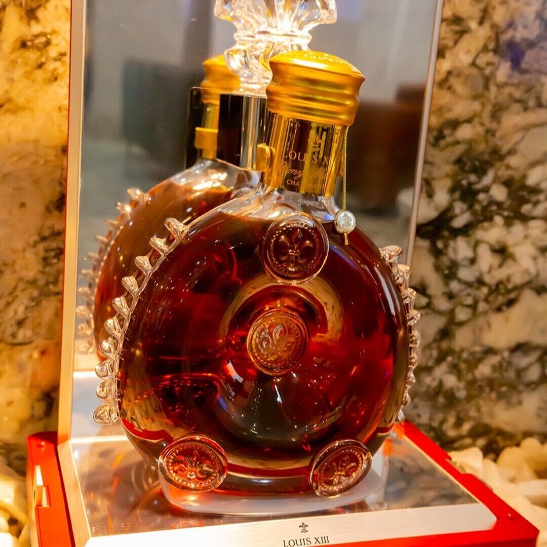 A bottle of Louis XII wine displayed in a glass case with a red label.