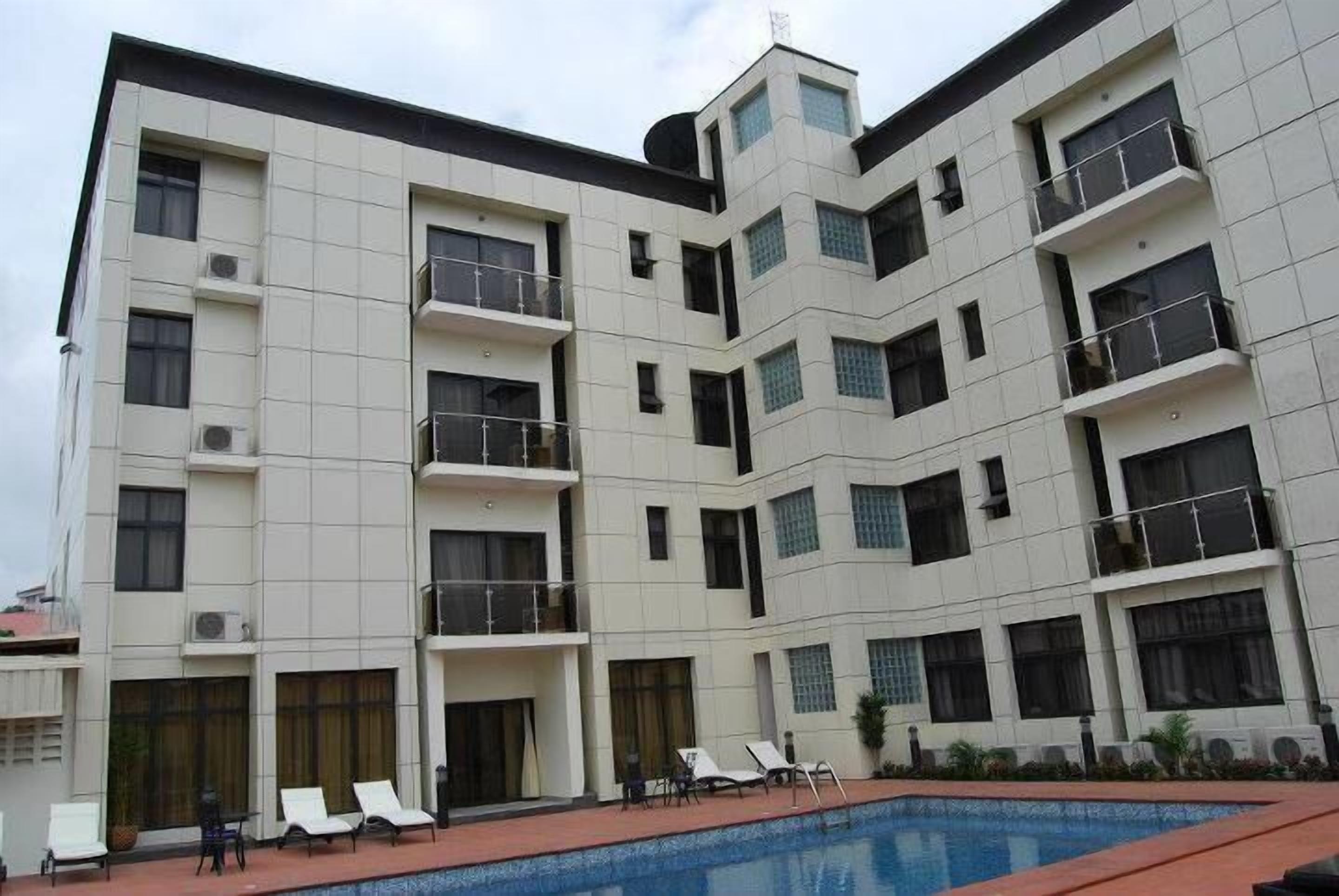 A multi-story hotel with a swimming pool, balconies, and air conditioning units.