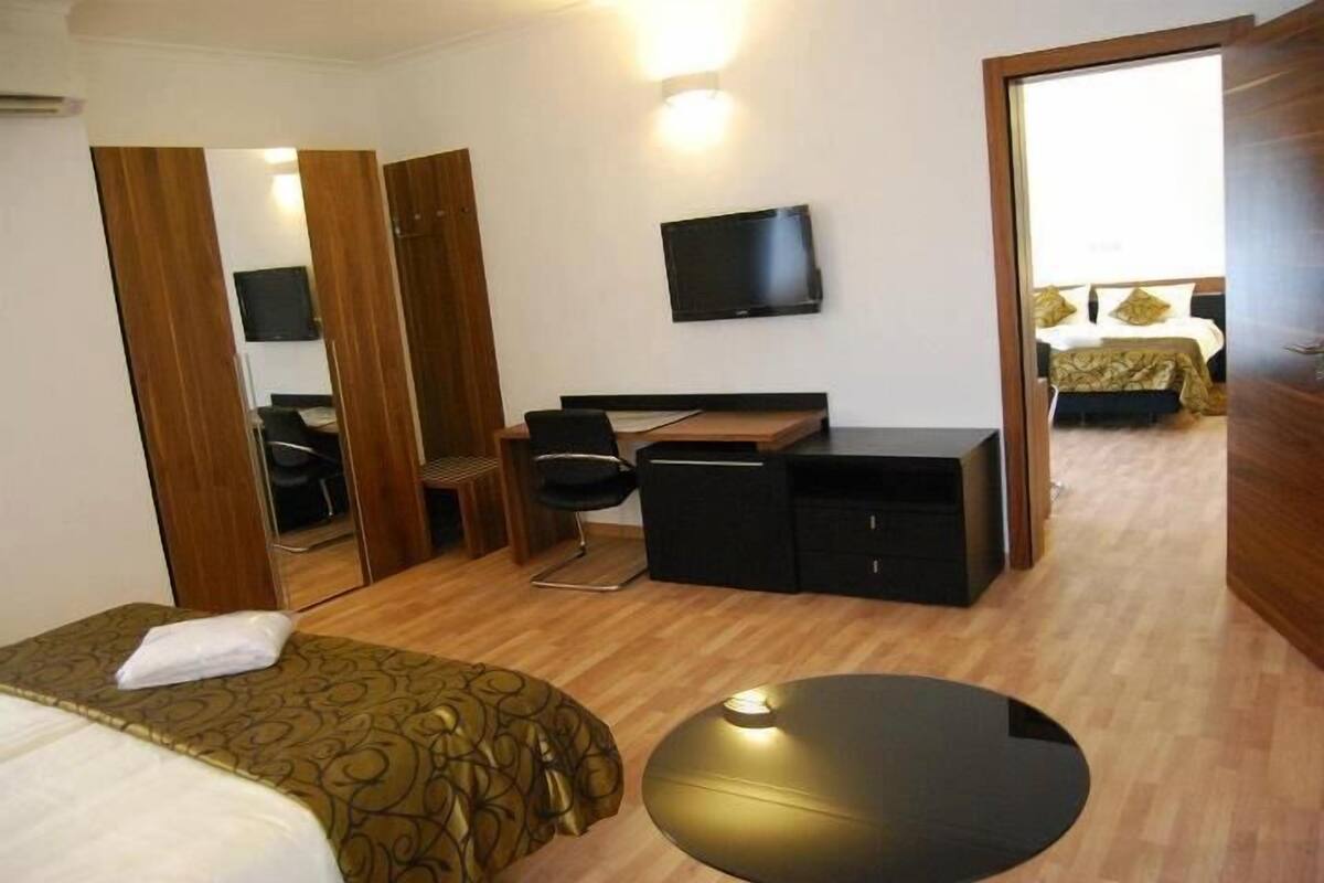 A hotel room with a bed, a desk, a chair, a TV, and a mirror.