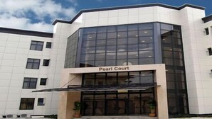 A building with a modern architectural style, featuring a prominent glass facade and a sign reading "Pearl Court." - Pearl Court Residence & Hotels (Lagos)