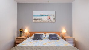 A bedroom with a bed, two bedside tables, two lamps, a painting, and a vase with flowers. - Gorgeous home in Valbandon with WiFi (Valbandon)