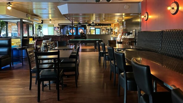 Interior de restaurante con cabinas, mesas y una zona de bar.