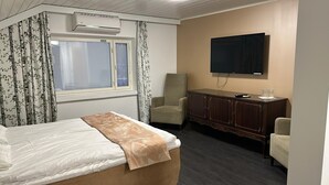 Una habitación de hotel con una cama, una silla, un televisor y un armario.