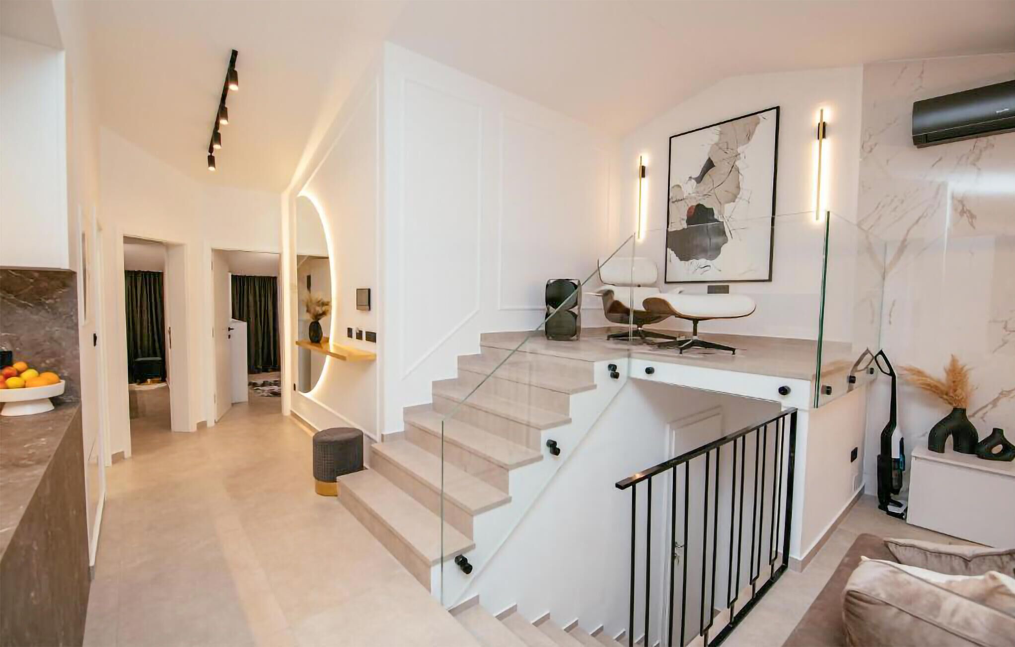 Eine moderne Treppe mit Glastrennstäben, minimalistisches Design und ein gerahmtes Kunstwerk darüber.