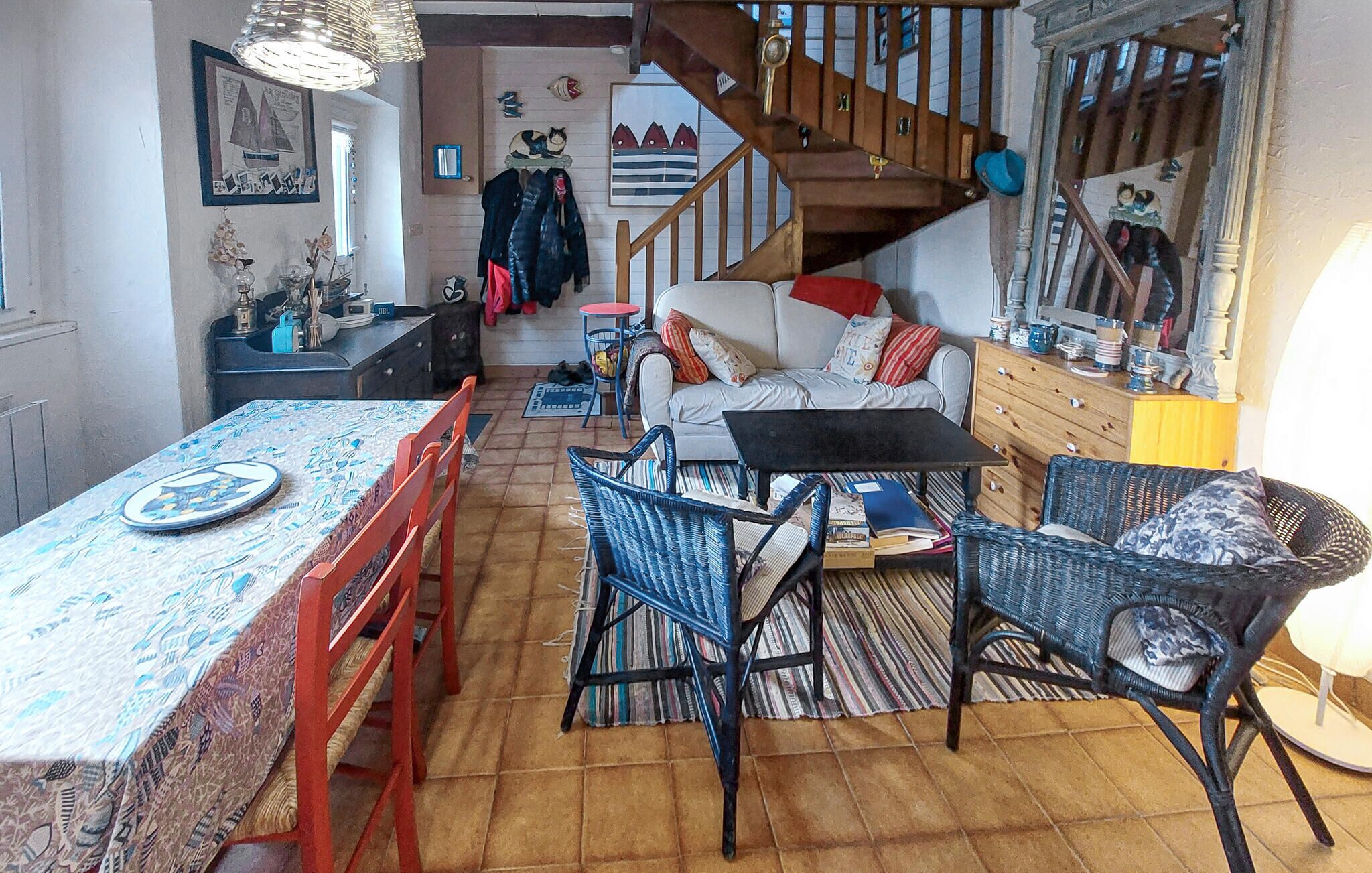 A cozy living room with a sofa, chairs, a dining table, and a staircase.