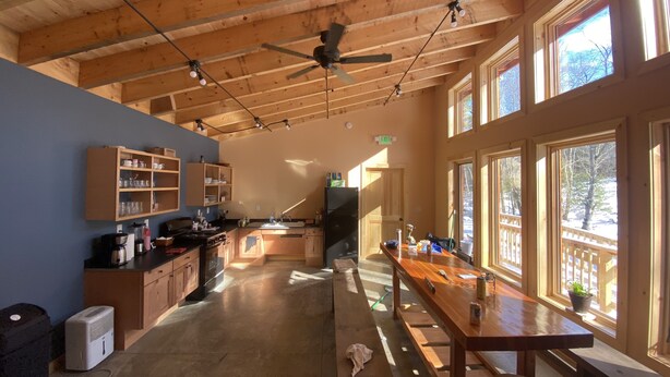 A spacious kitchen with wooden cabinets, a large island, and a dining area with benches. - Taborton Harvest Timber Trails
Unique cabin experience (Sand Lake)