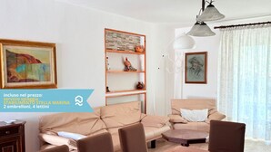 Ein Wohnzimmer mit Sofa, Sesseln, einem Tisch, einem Bücherregal und Kunstwerken.
