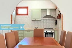 A compact kitchen with a dining area, featuring a tiled backsplash, a stove, and a window with a red frame. - VIVA1 - Numana, new five-room apartment in villa with swimming pool (Numana)