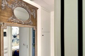 Una stanza con un grande specchio decorato, un armadio e una porta che dà su un'altra stanza.
