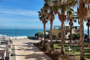 A coastal hotel with a patio, palm trees, and a view of the sea. - P018 - Porto Recanati, wonderful three-room apartment on the sea (Porto Reacanati)