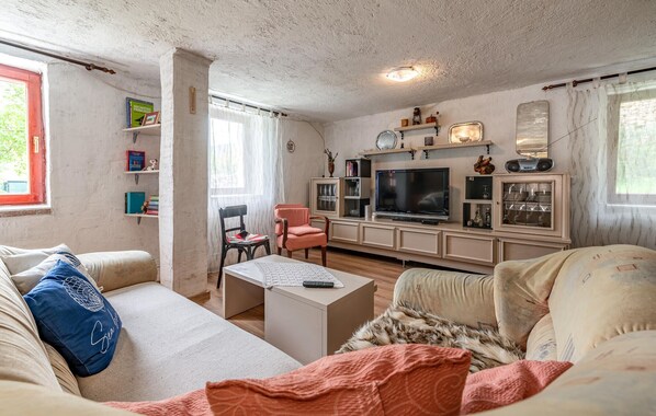 A living room with a sofa, a coffee table, a TV, and a bookshelf. - Pine Hill Holiday House (Gracac)