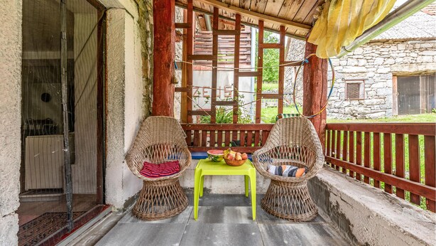 A covered outdoor seating area with wicker chairs and a bright green table.