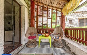 A covered outdoor seating area with wicker chairs and a bright green table. - Pine Hill Holiday House (Gracac)