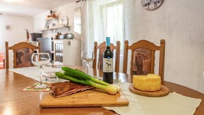 A dining table with a bottle of wine, a piece of cheese, and some vegetables.