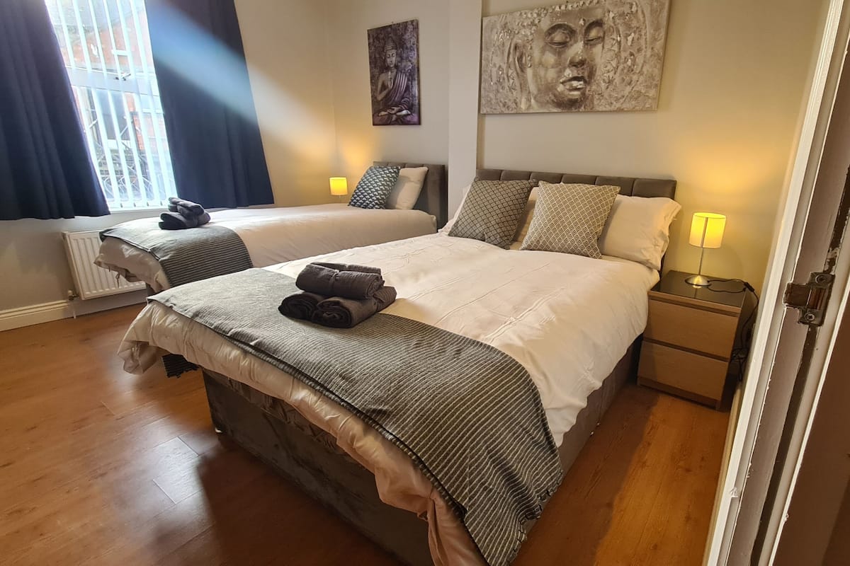 A double room with two beds, each with a headboard, bedside tables, and lamps.