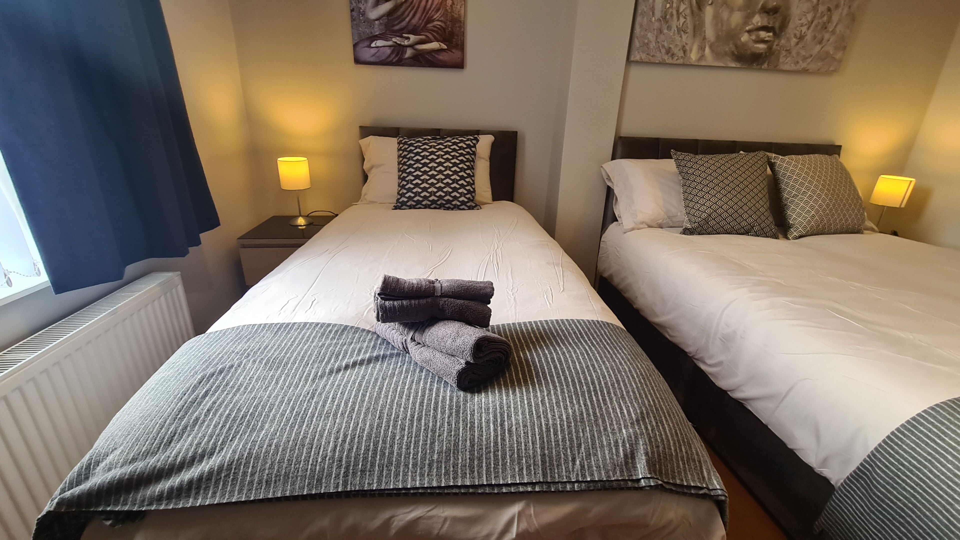 Ein Hotelzimmer mit zwei Betten, einem Heizkörper und zwei Nachttischlampen.