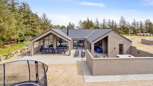 A modern house with a patio, a hot tub, and a dining area.