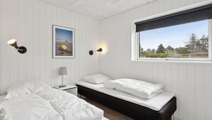 A bedroom with a bed, bedside table, lamp, and a framed picture on the wall.