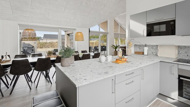 A modern kitchen with a large island, built-in appliances, and a dining area with a view.
