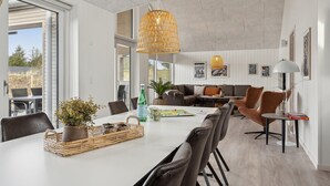 A modern dining area with a white table, wicker baskets, and a bottle of water.