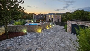 A stone-paved courtyard with a swimming pool, stone walls, and outdoor lighting. - Luxurious home in Biorine (Biorine)