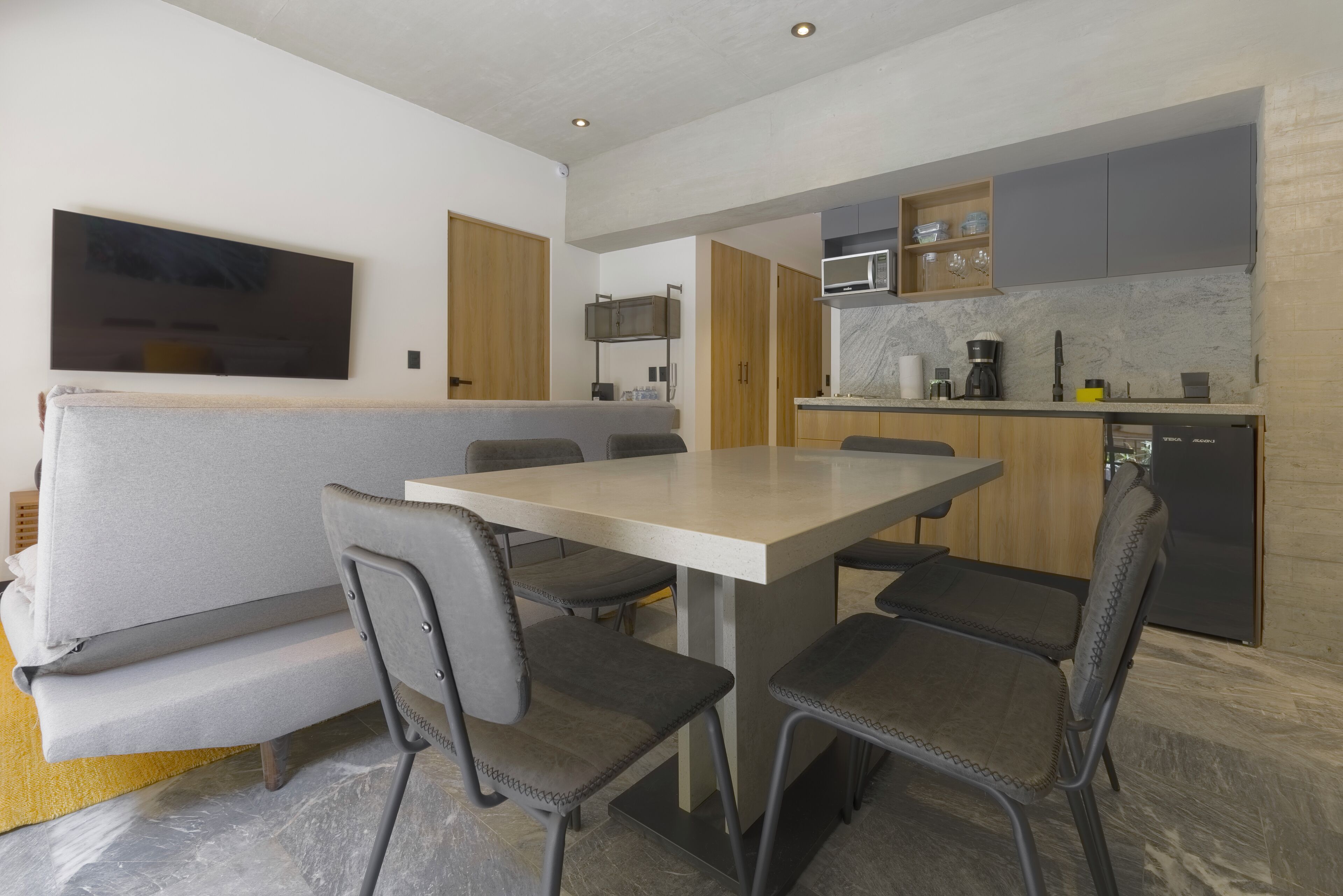 Una cocina moderna con comedor, armarios de madera, microondas y horno empotrado.