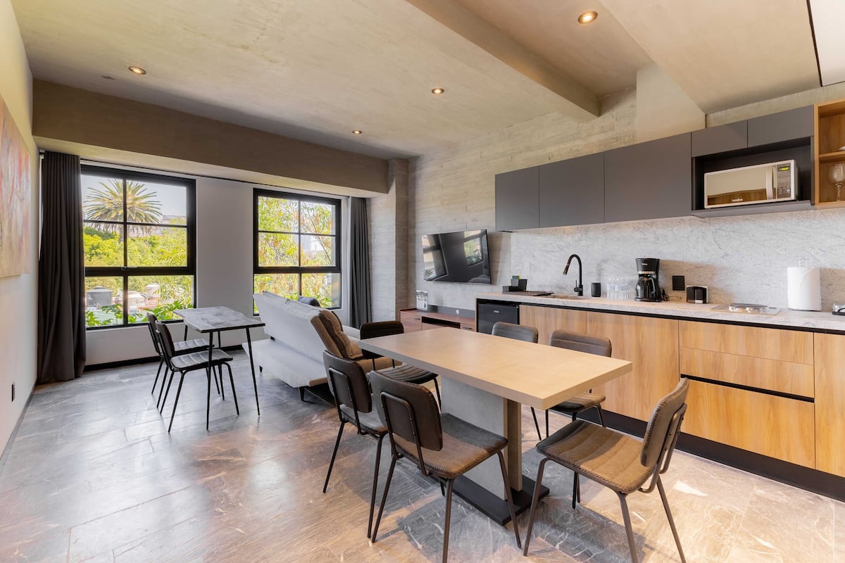 Una cocina moderna con una isla grande, electrodomésticos integrados y un comedor con una mesa larga y sillas.