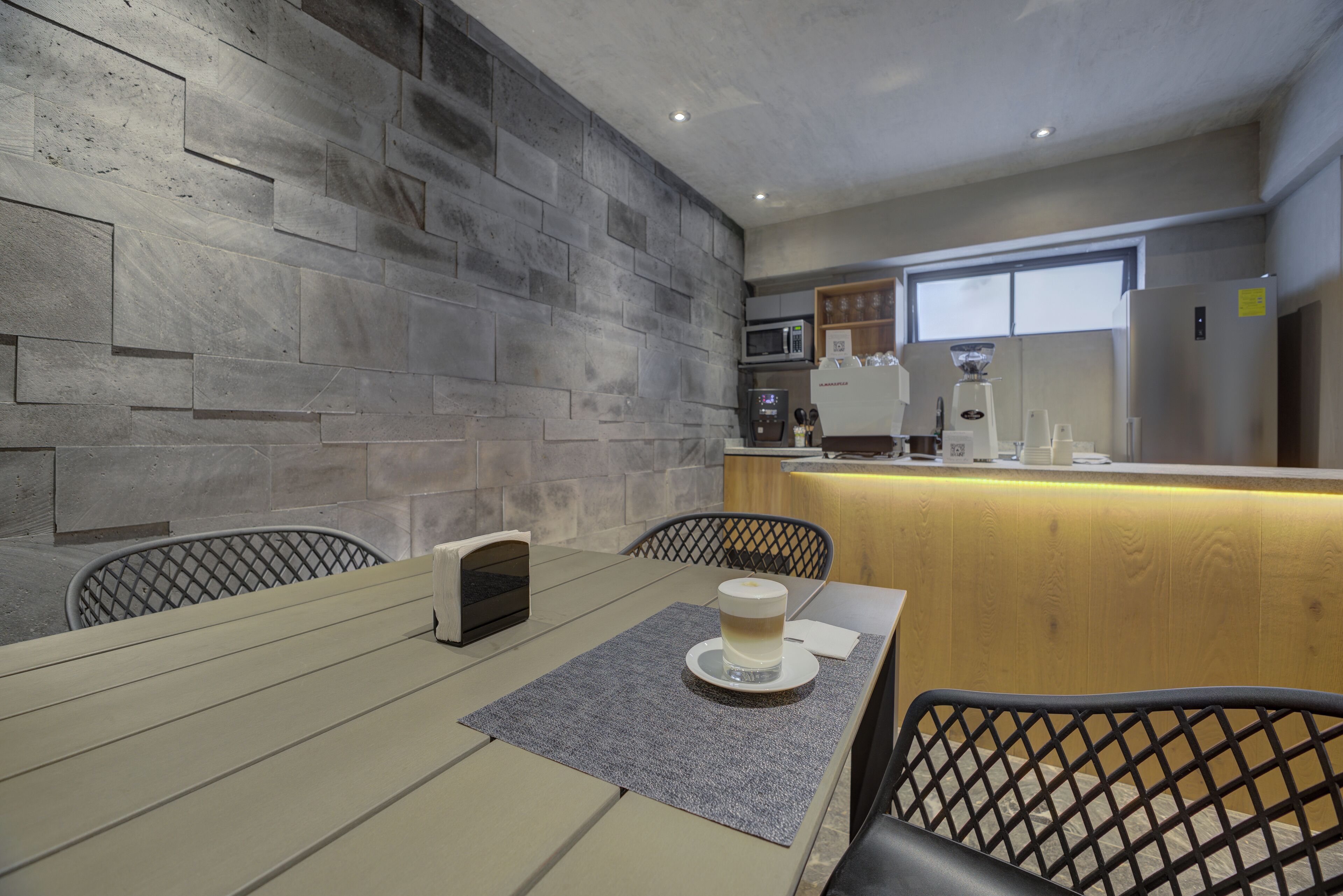 A modern kitchen with a stone wall backsplash, a wooden counter, and a seating area with a table and chairs.