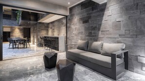 A modern interior with a stone wall, a sofa, a dining area, and a bar. - Park Condesa By Capitalia (Mexico City)