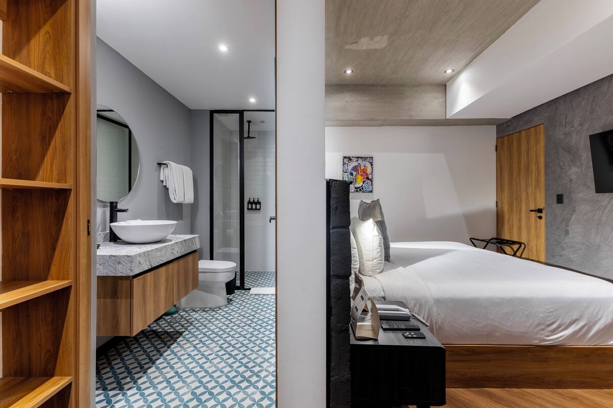 Un baño moderno con un tocador de madera, un lavabo blanco y un suelo con estampado azul.
