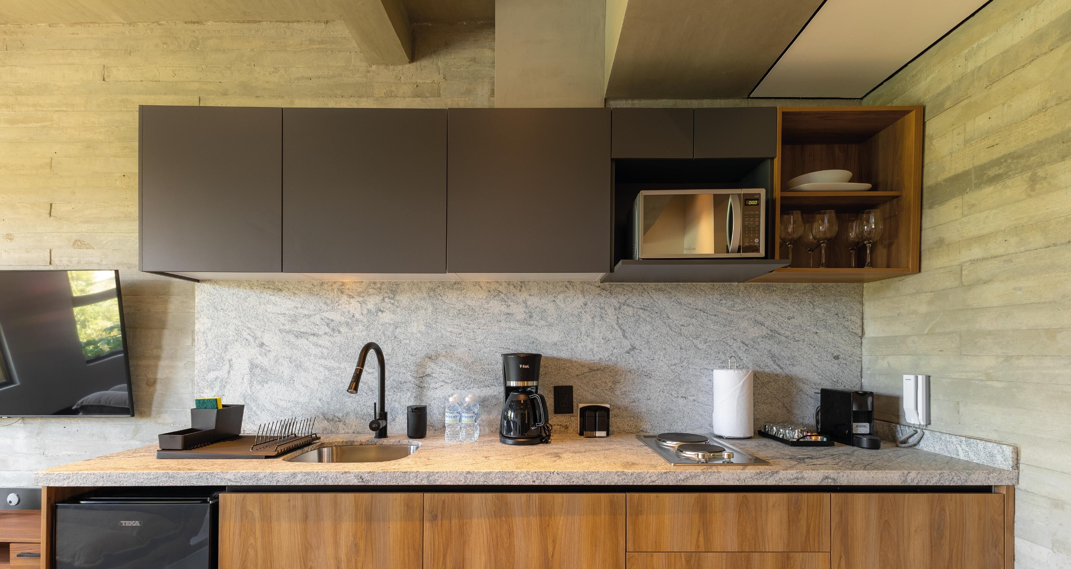 A modern kitchen with a granite countertop, stainless steel appliances, and wooden cabinetry.