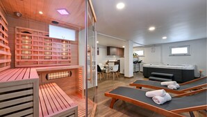 A sauna room with wooden benches and a glass partition, a dining area with a table and chairs, and a hot tub area with towels. - Amazing home in Lepoglava with sauna (Lepoglava)