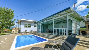 A modern pool area with a rectangular pool, lounge chairs, and a covered patio with outdoor seating. - Amazing home in Lepoglava with sauna (Lepoglava)