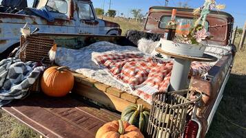 Un letto rustico con una coperta a quadri, una panca di legno e una zucca.