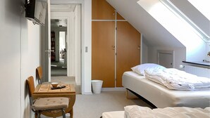 Ein Hotelzimmer mit einem Bett, einem Schreibtisch mit Stuhl, einem kleinen Tisch und einem Kleiderschrank.