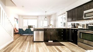 A modern kitchen with dark cabinets, stainless steel appliances, and a wooden floor. - ☆Mediterranean Retreat☆King Bed★Fireplace★Garage (Edmonton)