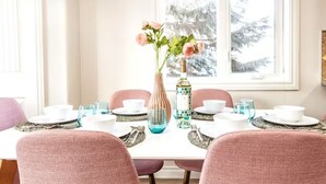 A dining table set with pink chairs, white plates, and a vase with flowers. - ☆Mediterranean Retreat☆King Bed★Fireplace★Garage (Edmonton)