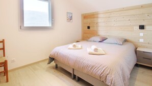 A bedroom with a bed, wooden headboard, a window, a chair, and a small painting on the wall. - Pretty new and comfortable house between towns and lakes (Voglans)