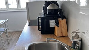 A kitchen with a stainless steel sink, a coffee maker, a knife block, and a water dispenser.
