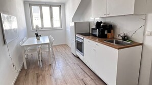 A compact kitchen with white cabinets, a wooden countertop, a built-in oven, and a window.