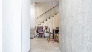 A hallway with a staircase, a dining area with a table and chairs, and a wall with vertical wooden slats.