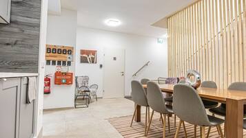 Een moderne eetruimte met een houten tafel en stoelen, een brandblusser en rookmelder aan de muur.