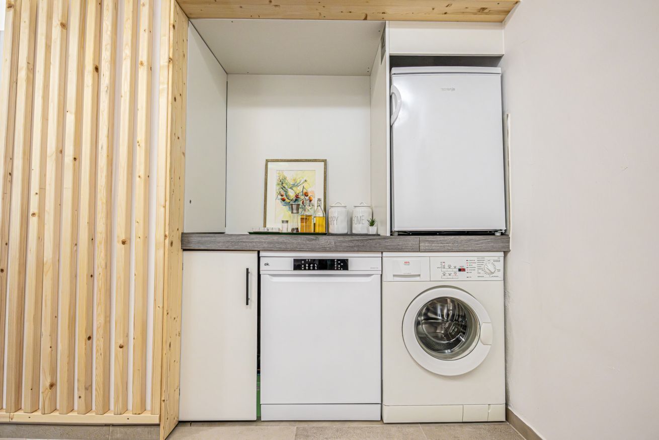 Een kleine keuken met een vaatwasser, wasmachine en koelkast.
