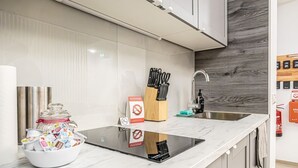 Una cocina moderna con encimera de mármol, pileta de acero inoxidable y protector de cocina de madera.