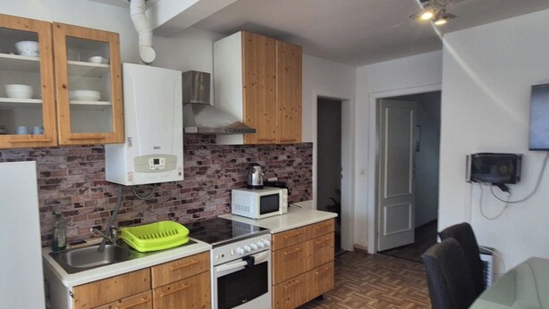 A compact kitchen with a refrigerator, stove, microwave, and wooden cabinets.