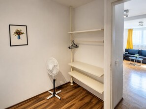 A room with wooden flooring, a white fan, a white shelving unit, and a framed picture on the wall. - Vienna Wanderlust: 2 BR Apt in the Heart of It All (Vienna)