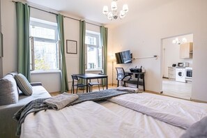 Une chambre à coucher comprenant un lit, un bureau, une chaise, un téléviseur et donnant sur une buanderie.