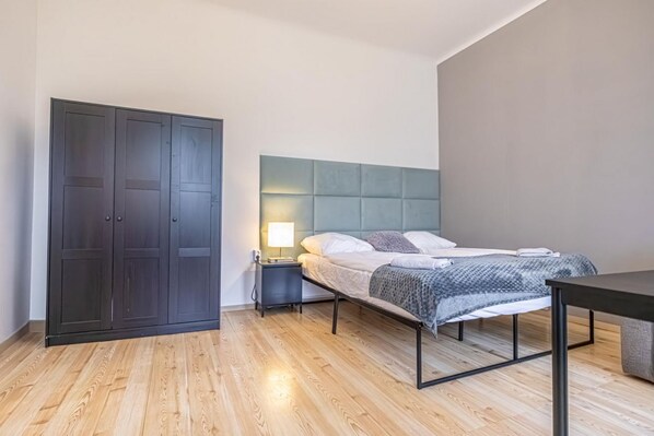 Une chambre à coucher comprenant un lit, une table de chevet, une lampe, une armoire et une table.