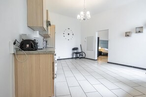 A modern kitchen with a built-in coffee maker, a clock on the wall, and a chandelier.