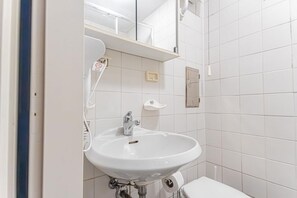 Ett badrum med ett vitt handfat, en toalett och en spegel ovanför handfatet.